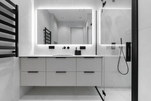 a white bathroom with a sink and a mirror at Hygge Sand Apartment in Vilnius