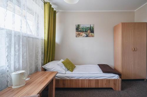 a small bedroom with a bed and a wooden table at OW Jaskółka in Zakopane