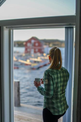 a woman looking out a window at the water at Norsk Havbrukssenter - Rorbuer in Brønnøysund