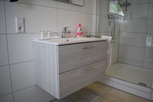 La salle de bains blanche est pourvue d'un lavabo et d'une douche. dans l'établissement Ferienwohnung (H)Auszeit Pape, à Winterberg