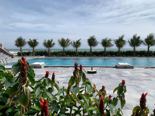 a large swimming pool with palm trees in the background at Bờ Biển Vàng Resort in Ke Ga