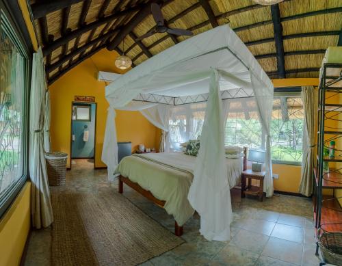 1 dormitorio con 1 cama grande con dosel en Maramba River Lodge, en Livingstone