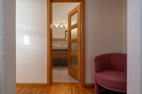 a room with a red chair and a mirror at Funtnatsch Apartment Langkofel in Laion