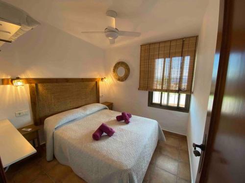 Casa rural junto al mar في بينالمادينا: غرفة نوم مع سريرين مع أقواس أرجوانية عليها