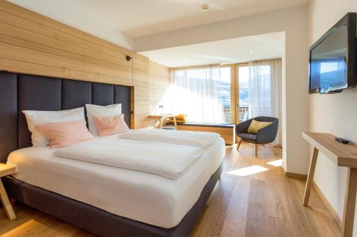a hotel room with a large bed and a television at Granpanorama Hotel StephansHof in Villandro