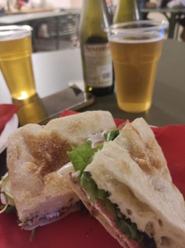 a sandwich on a plate with two glasses of beer at Ostello Ossigeno in Campodimele