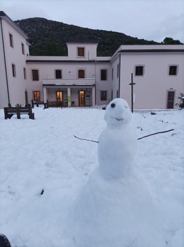 a snowman sitting in the snow in front of a building at Ostello Ossigeno in Campodimele