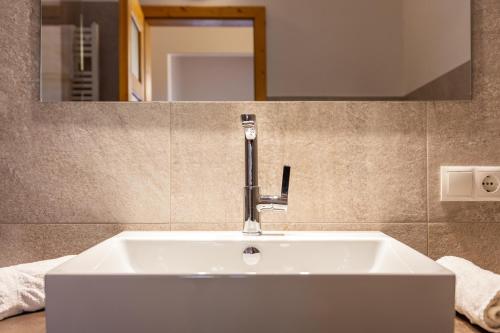 a white sink in a bathroom with a mirror at Funtnatsch Apartment Langkofel in Laion