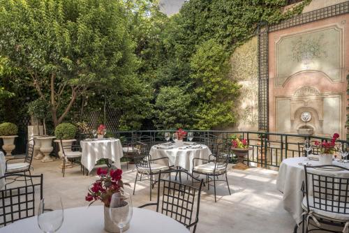 Relais & Châteaux Hotel Orfila في مدريد: فناء في الهواء الطلق مع طاولات وكراسي وأشجار