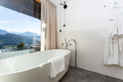 a white bath tub in a bathroom with a window at Granpanorama Hotel StephansHof in Villandro