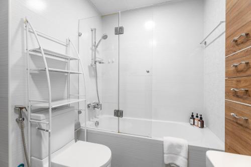 a white bathroom with a shower and a toilet at Nasma Luxury Stays - Sleek City Haven 1BR in Dubai's Glitz Residence 3 in Dubai