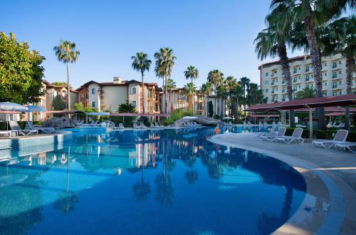 uma piscina num hotel com cadeiras e palmeiras em Miramare Queen Hotel em Side