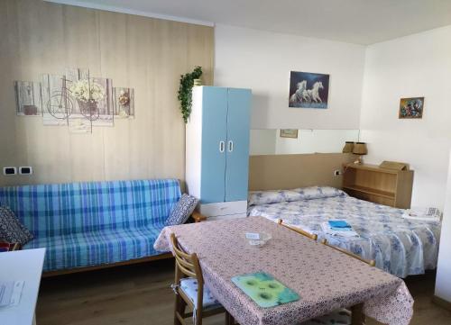 a room with a table and a refrigerator and a bed at Appartamenti Codàn in San Vito di Cadore