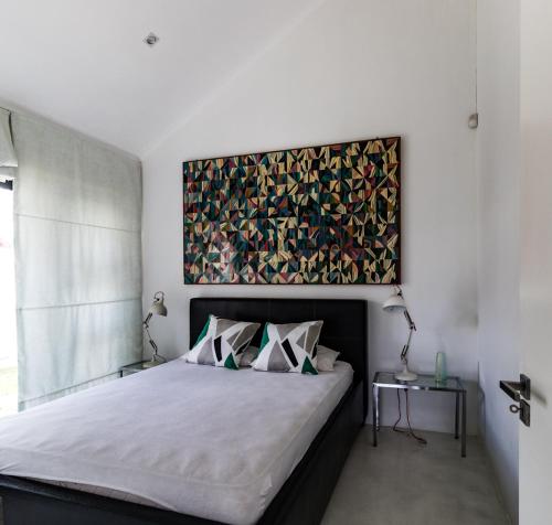 a bedroom with a bed with a painting on the wall at Leisure Isle 2 bedroom home with essential power. in Knysna