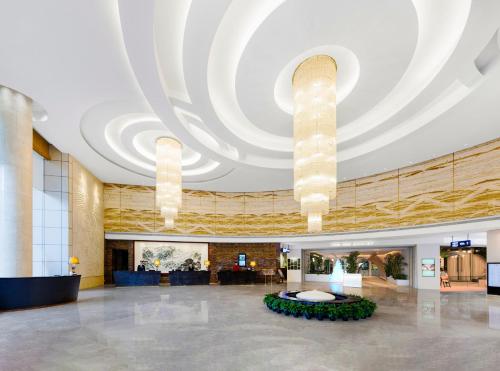 een grote lobby met een groot plafond met kroonluchters bij Vanburgh Hotel - Free shuttle bus transfer during Canton Fair in Guangzhou