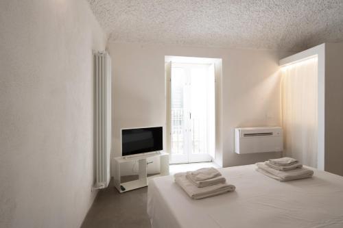um quarto branco com uma cama e uma televisão em AUREA tempio di Apollo em Siracusa