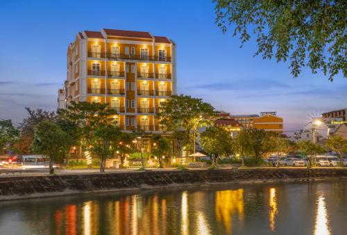 un edificio alto junto a un río por la noche en Royal Riverside Hoi An Hotel & Spa, en Hoi An