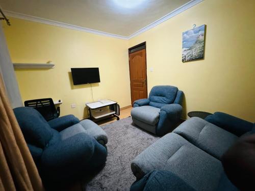 un salon avec des canapés bleus et une télévision dans l'établissement Lovely 2 Bedroom Apartment in Ongata Rongai, à Langata Rongai