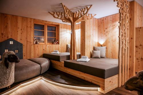 twee bedden in een kamer met een boom aan de muur bij Family Hotel Posta in Santa Cristina in Val Gardena
