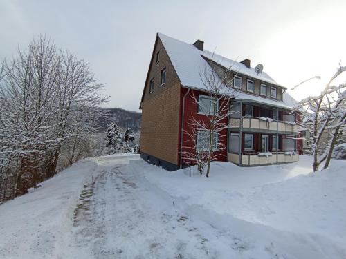 una casa en una colina cubierta de nieve con una carretera en Haus Christoffel Wieda, en Wieda