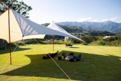 two people laying on the grass under a large white tent at Wind and horn Private villa with Mt tanigawa view in Komatsu