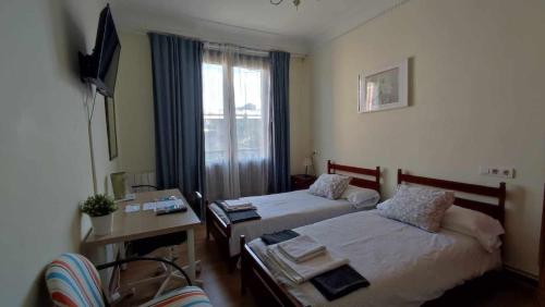 1 Schlafzimmer mit 2 Betten, einem Schreibtisch und einem Fenster in der Unterkunft FlipHouse Rooms Pensión in Bilbao