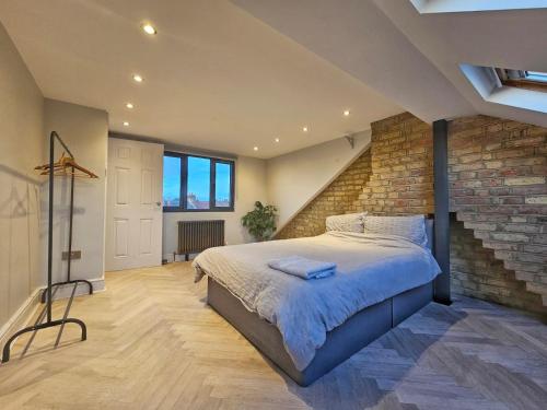 ein Schlafzimmer mit einem großen Bett mit Ziegelwand in der Unterkunft Contemporary 3 bed house with spacious garden close to Stratford & Canary Wharf in London