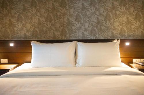 a bed with white pillows in a bedroom with a wallpaper at Singharaj Boutique Hotel in Chiang Mai