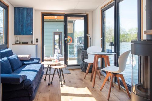 a living room with a couch and a table and chairs at Undine - Wunderschönes Tiny Hausboot in Hamburg