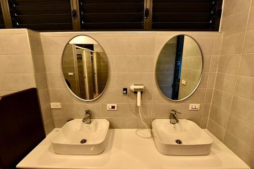 a bathroom with two sinks and two mirrors at Oceans Explore Hostel in Green Island
