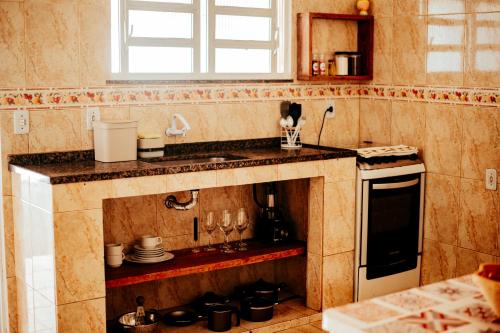 eine Küche mit einer Spüle und einer Theke mit Geschirr in der Unterkunft Casa tamanho família com Garagem, Churrasqueira e Redes de Descanso in Búzios