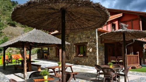 a patio with tables and umbrellas in front of a house at Apartamentos Rurales & Spa La Bárcena in Enterria