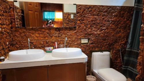 a bathroom with two sinks and a mirror and a toilet at Flores Garden Hotel in Coron