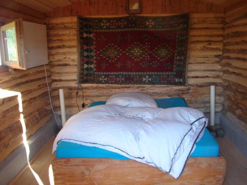 a bed in a cabin with a rug on the wall at Blockhaus im Permakulturgarten in Argenbühl