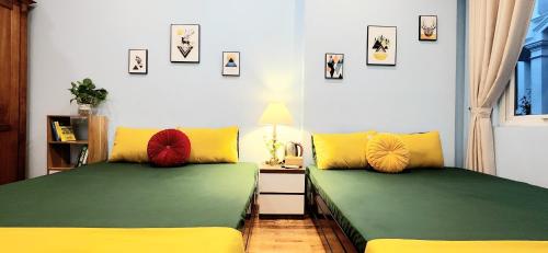 two beds with green and yellow pillows in a room at Hanoi Cozy Homestay Long Biên in Hanoi