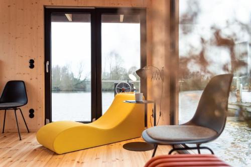 a living room with a yellow couch and chairs at Dein Hausboot OFF für deine Auszeit in Hamburg in Hamburg
