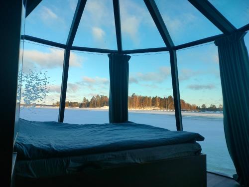 a bed in a room with a large window at Aurora Hut Savonlinna in Savonlinna