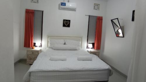 a bedroom with a large bed with two pillows on it at Neny's Homestay in Saba