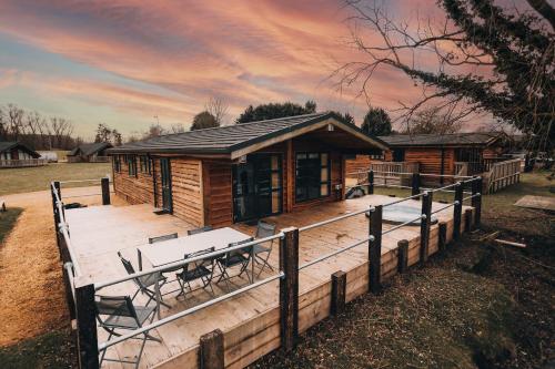 a wooden cabin with a table and chairs on a deck at Woodlakes Park By Liv Retreats in Kings Lynn