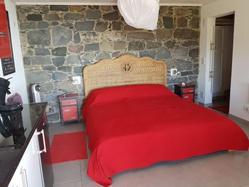 a bedroom with a red bed with a stone wall at Lucky Lemons - Boutique Houses Madeira (Studio) in Calheta