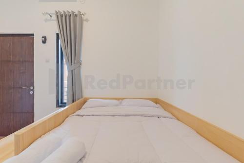 a bed in a white room with a window at Rumah Panda Guesthouse RedPartner in Tangkil