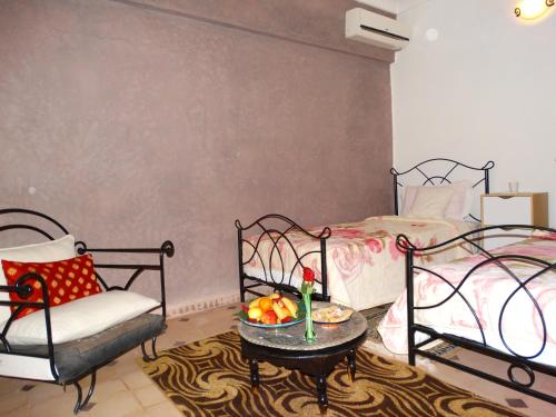 een slaapkamer met 2 bedden en een tafel met een fruitschaal bij L'AUBERGE DES REMPARTS in Marrakesh