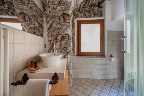 a bathroom with a sink and a stone wall at Pietra Rara Apartments in Pietramurata
