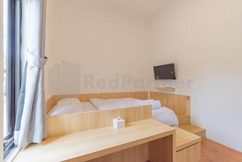 a bedroom with a bed with a desk and a television at Rumah Panda Guesthouse RedPartner in Tangkil