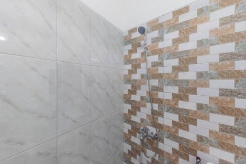 a bathroom with a shower with marble tiles at Rumah Panda Guesthouse RedPartner in Tangkil