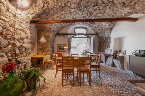 a dining room with stone walls and a table and chairs at Pietra Rara Apartments in Pietramurata