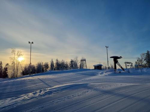 a snow covered slope with a ski lift in the distance at Outdoor Hostel Laajis in Jyväskylä