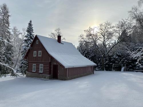a red barn with snow on the roof at Chalupa Janovice in Rudník