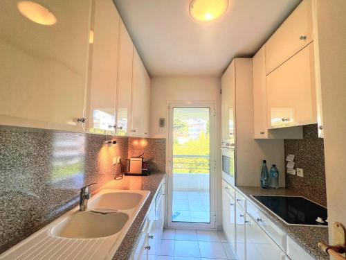 une cuisine blanche avec deux éviers et une porte dans l'établissement Ambre d' Or apartment by Welcome to Cannes, à Cannes