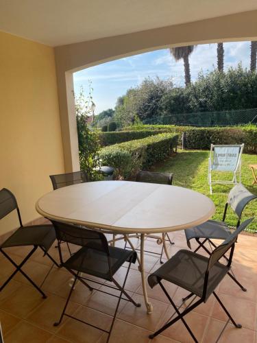 - une table à manger avec des chaises et une vue sur la cour dans l'établissement Le jas de Pépoune, à La Croix-Valmer